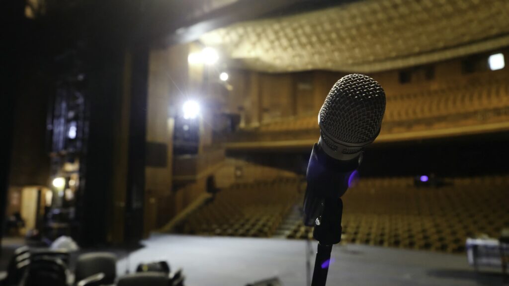 Microphone on the stage and empty hall during the rehearsal. Microphone on stage with stage-lights